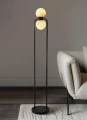 Designerska lampa stojąca z alabastru i czarnego metalu, która tworzy miękkie światło i podkreśla minimalistyczny charakter aranżacji.